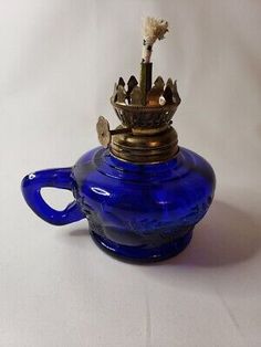 a blue glass tea pot with a gold crown on it's top and handles