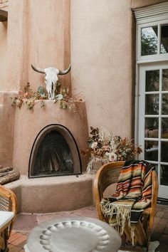 a living room with a fire place and some chairs in front of the fireplace that has a cow skull on it