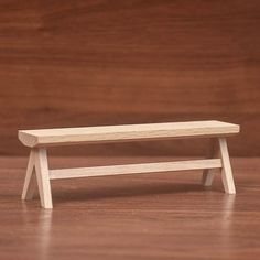 a small wooden bench sitting on top of a hard wood floor next to a wall