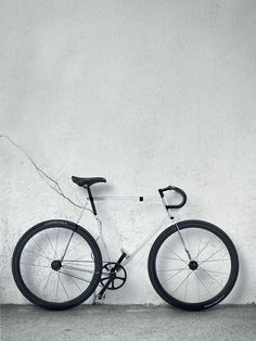 a black and white photo of a bike leaning against a wall