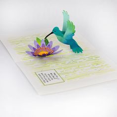 a paper sculpture of a hummingbird hovering over a flower