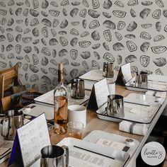 the table is covered with books, cups and utensils in front of a wallpapered background