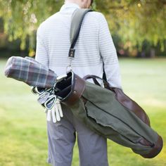 a man carrying a duffel bag in the park with his hat and gloves on