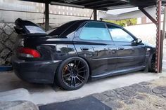 the back end of a black car parked in a garage