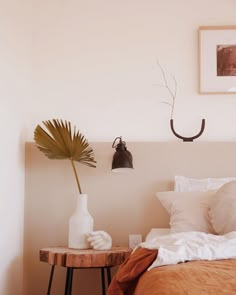 a bed with white sheets and pillows in a bedroom next to a wall mounted light