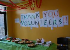 a green table topped with lots of pastries next to a sign that says thank you volunteers