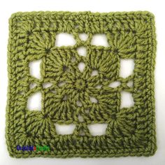 a green crocheted square is shown on a white surface