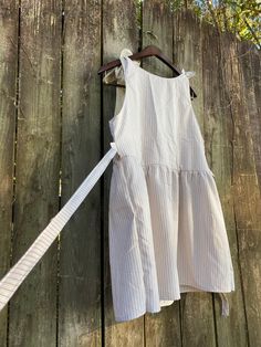 a white dress hanging on a wooden fence