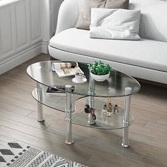 a glass coffee table sitting on top of a wooden floor next to a white couch