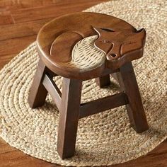 a wooden stool with an animal carved on the top and bottom, sitting on a rug