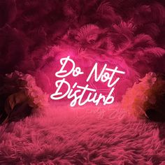 the words do not disturb are lit up in front of a pink background with lots of feathers