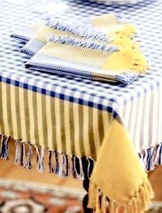 a blue and white table cloth with tassels on it, sitting on top of a rug