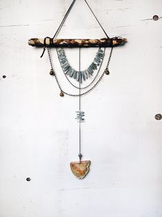 a piece of wood hanging from a wall with beads and chains attached to it's sides