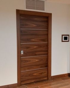 a wooden door in the corner of a room with tile flooring and white walls