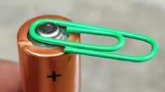 a close up of a person holding a battery with a green ring on it's end