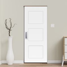 an empty room with a white door and vase on the floor, next to it