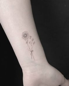 a small daisy tattoo on the wrist