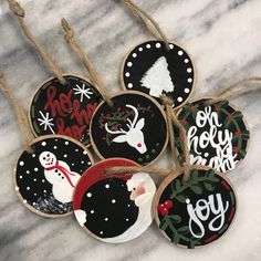 christmas ornaments are hanging from twine on a marble counter top, decorated with black and white designs