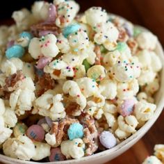 white chocolate popcorn with sprinkles and candies in a bowl on a wooden table