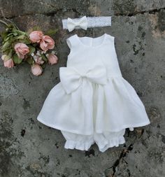 This beautiful ivory baptism outfit, will have your little one looking as adorable as can be on her christening day. The christening dress is completed with bloomers and a lace headband, featuring an adorable linen bow. The bodice of this baby flower girl dress is lined with a soft cotton fabric, while the skirt is kept unlined, keeping this baby girl linen dress beautifully flowy. An ivory bow decorates the waist of the baby dress, and sash tails are sewn into side seams. By tying them to a big Baby Flower Girl Dress, Christening Outfit Girl, Baby Christening Dress, Baby Christening Outfit, Baby Baptism Dress, Girls Baptism Dress, Baptism Dress Baby Girl