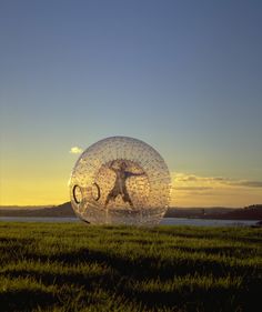 a person is standing in the middle of a field with a large object behind them