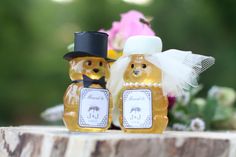 two honey jars sitting next to each other on top of a wooden table with flowers in the background