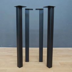 three tall black metal poles sitting on top of a hard wood floor