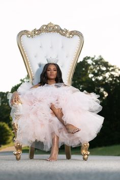 a woman sitting in a white chair with a tiara on her head and legs