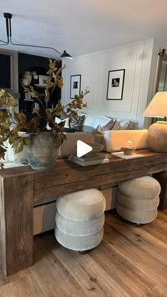 a living room filled with furniture and a wooden table topped with vases on top of it