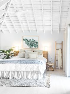 a bed with white sheets and pillows in a bedroom next to a painting on the wall