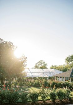 the sun shines brightly in front of a house with flowers and trees around it