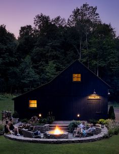 an outdoor fire pit in the middle of a yard with chairs around it at night