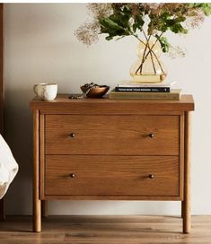 a nightstand with flowers and books on it