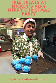 a man wearing a santa hat and holding up some blue christmas baubies with the words free treats at mickey's very merry christmas party