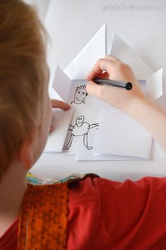 a young boy drawing on paper with a marker