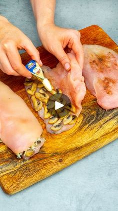 a person is cutting up some meat on a wooden board with other food items in front of them