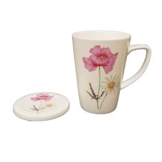 a white coffee cup with pink flowers painted on the side, next to a plate