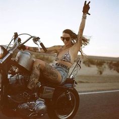 a woman riding on the back of a motorcycle with her arms up in the air