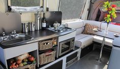 a kitchen area with sink, stove and cabinets in a camper van or truck