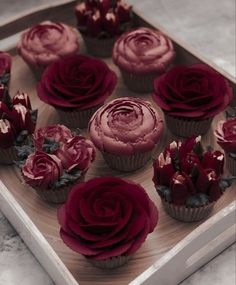 cupcakes decorated with red frosting and roses on a wooden tray, ready to be eaten