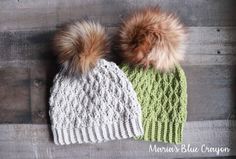 two knitted hats with pom - poms on them, one green and the other white