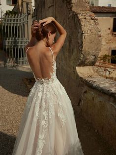 the back of a woman's wedding dress in front of an old stone building