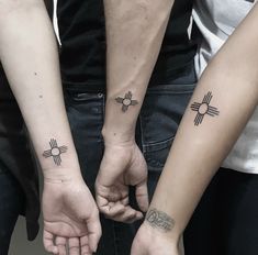 two people are holding hands with tattoos on their arms and the other hand has an arrow