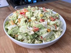 a white bowl filled with salad sitting on top of a wooden table