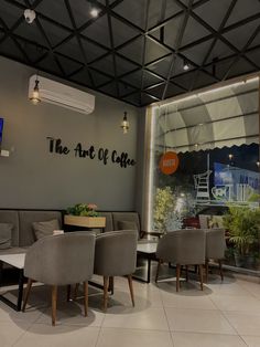 the interior of a restaurant with chairs and tables in front of a large window that reads the art of cafe