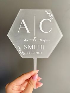 a clear acrylic wedding cake topper with the initials and date on it