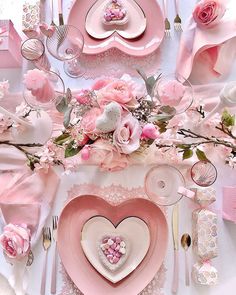 the table is set with pink flowers and plates