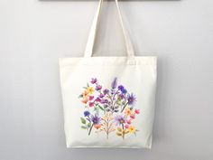 a tote bag hanging on a wall with flowers painted on it