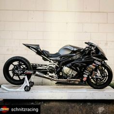 a black motorcycle parked in front of a white brick wall