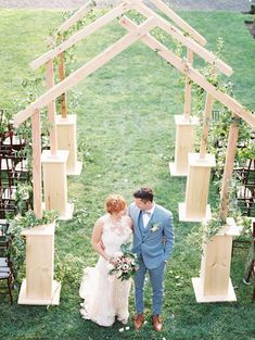 a bride and groom standing in front of an arch made out of wooden planks